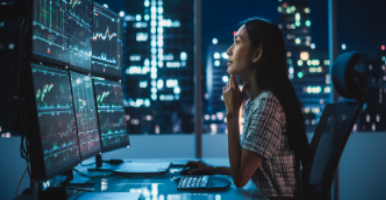 woman studying data on computer screens at night